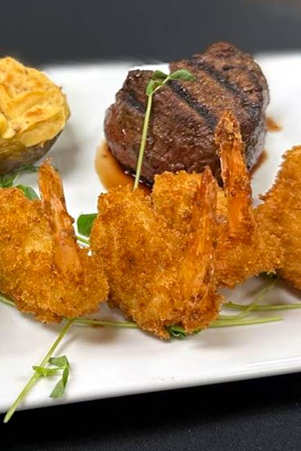 Breaded fried shrimp, grilled steak, and twice-baked potato at our Marinette Restaurant.