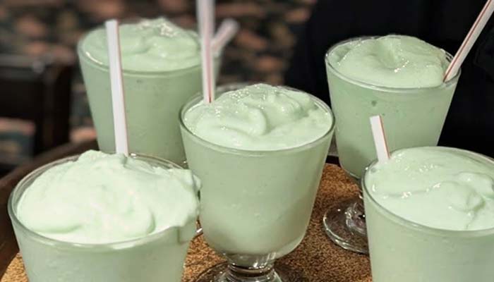 Five light green milkshakes with straws, served on a tray at Marinette Restaurant.