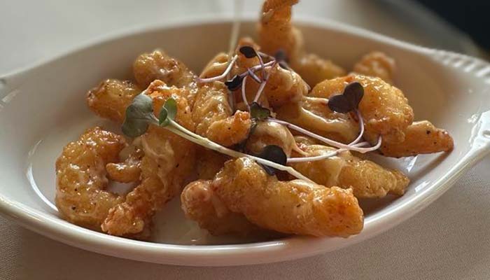 Fried calamari with sauce and microgreens, served at Marinette Restaurant in a white dish.